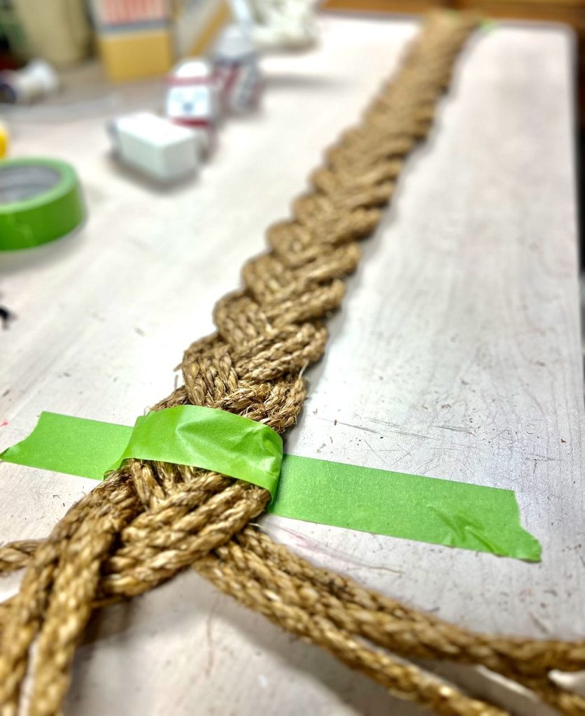 a long braid of jute rope is taped to a table top