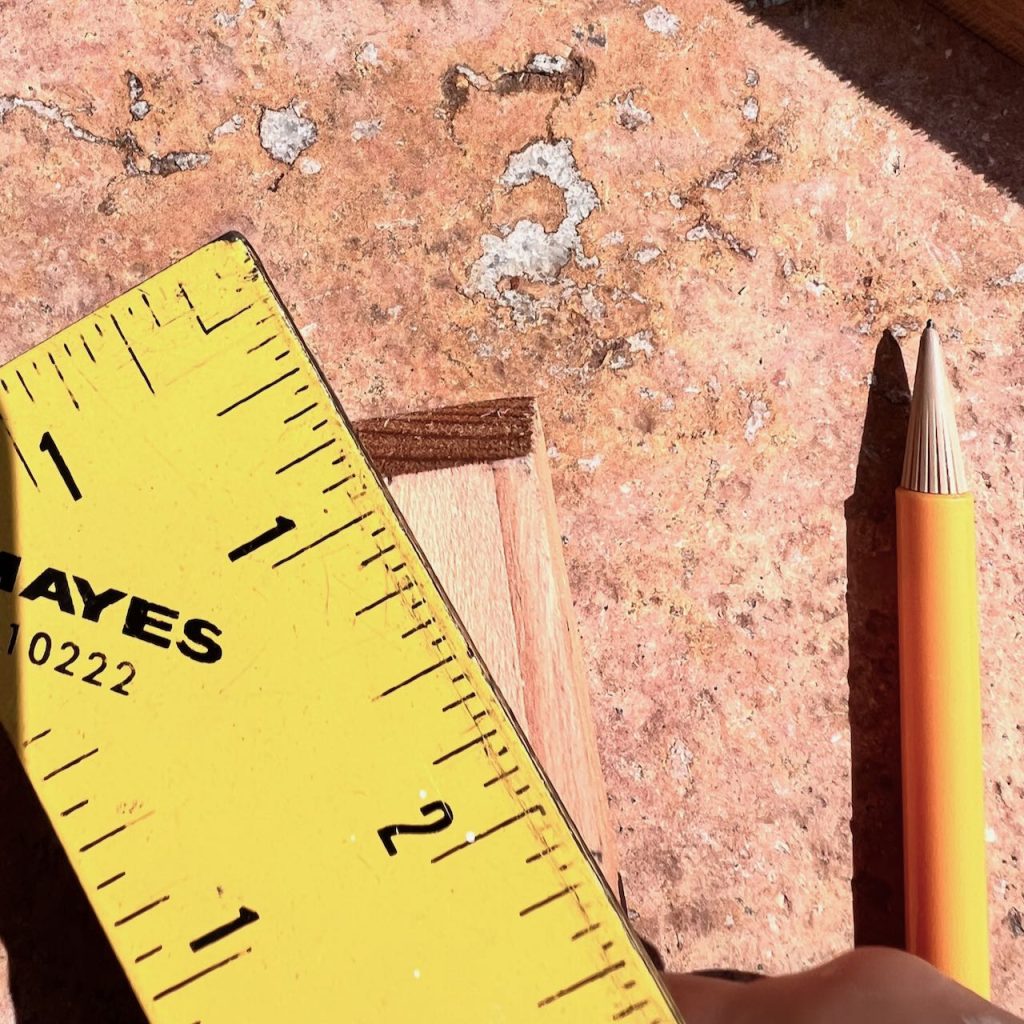 closeup of a ruler on a small wooden block and a pencil beside it