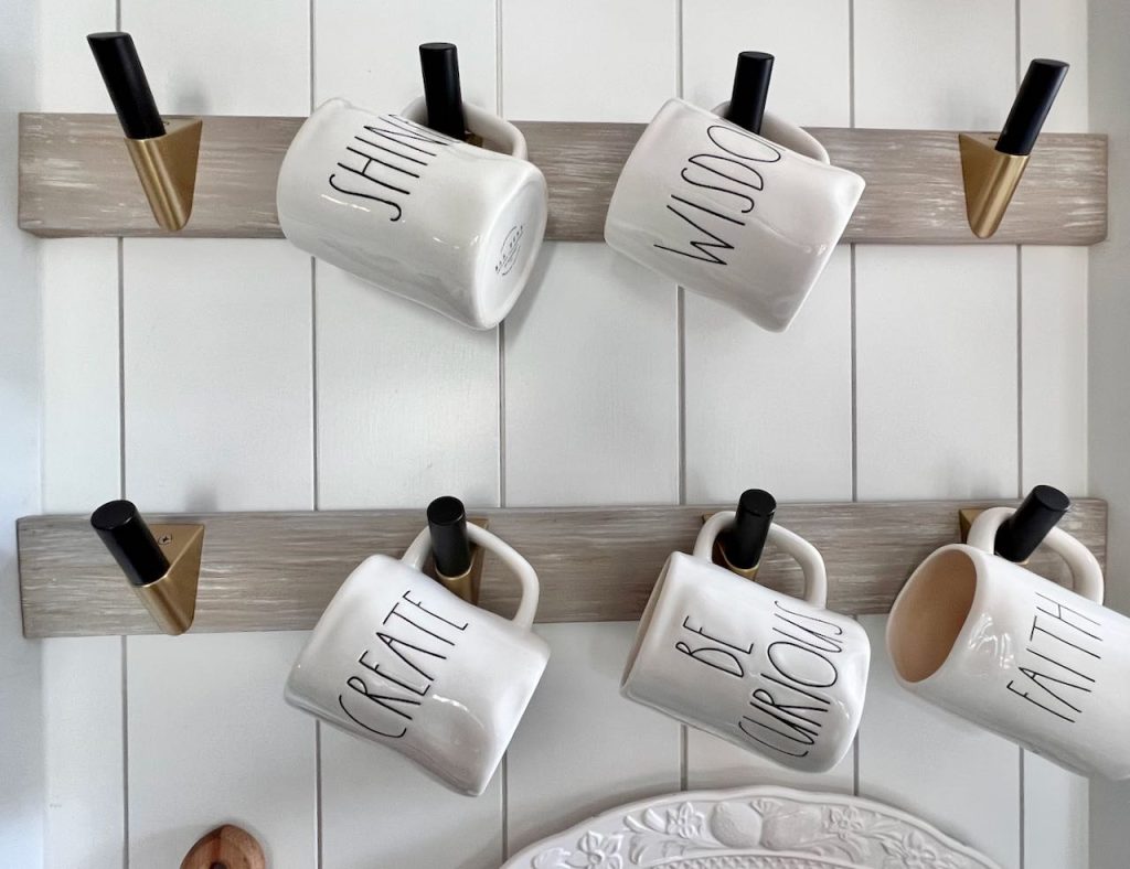 Close up of Rae Dunn Mugs hanging on hooks installed on lengths of wood