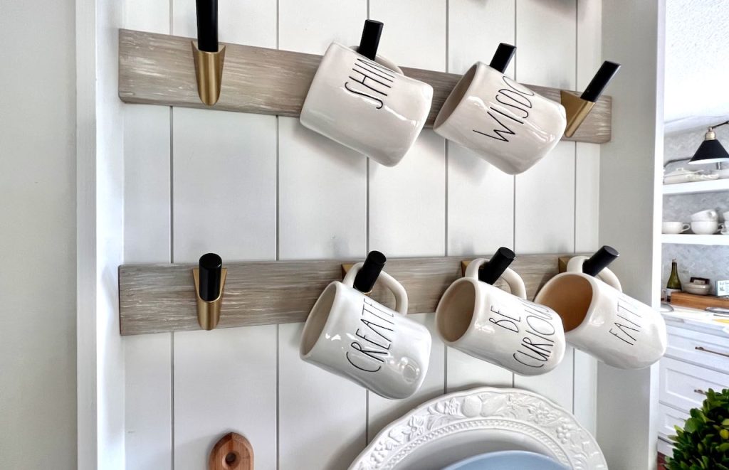 Coffee Cups Hanging On Hooks In Front Of Brick Wall Stock Photo