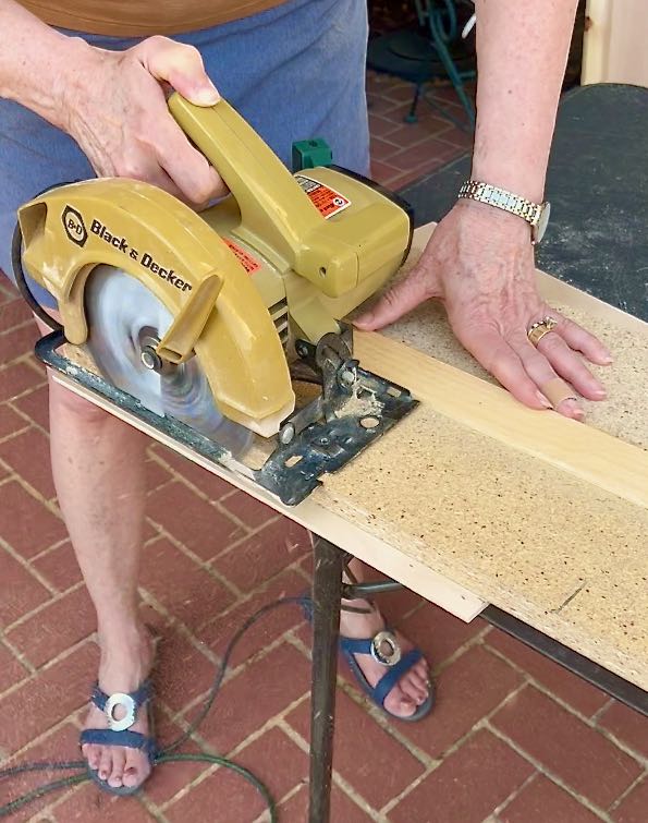 woman is using a circular saw on a cutting jig to cut plywood