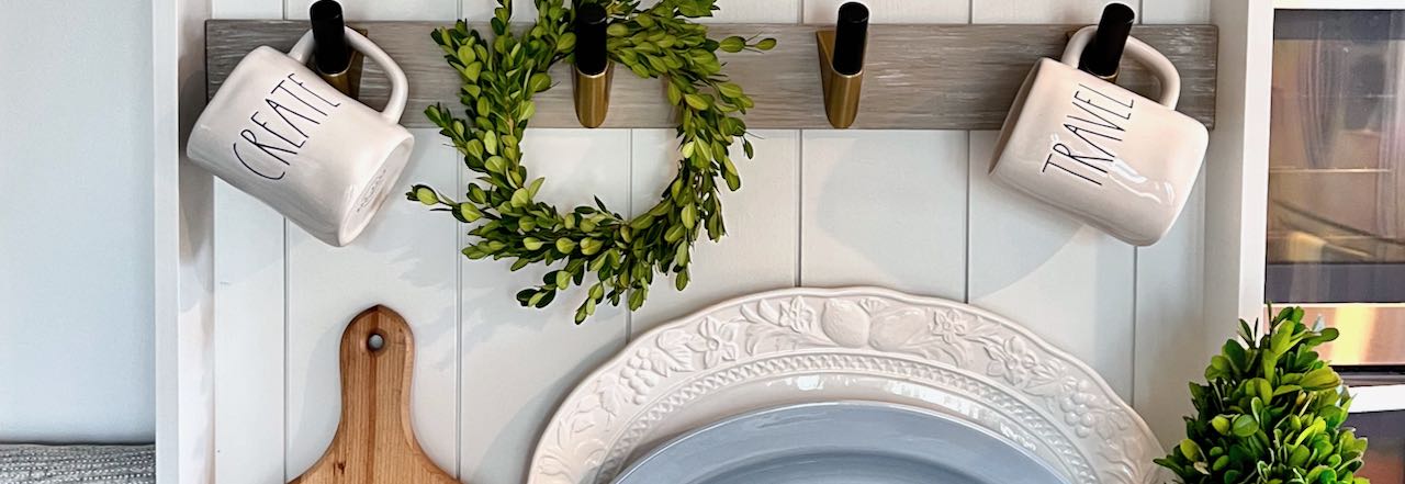 wide closeup of a fresh boxwood wreath hanging on a mug and plate wall rack