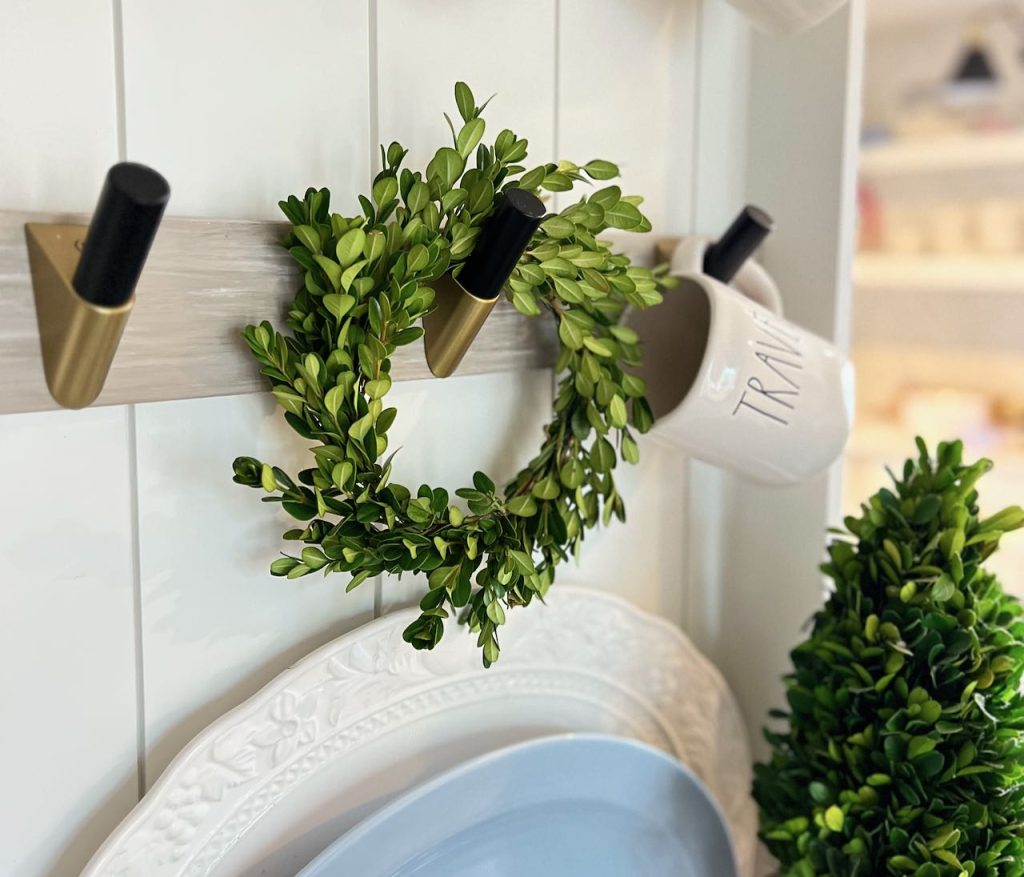 closeup of a fresh boxwood wreath hanging on a mug and plate rack