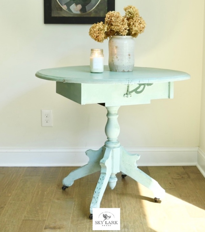 antique table in pale seafoam green is in a sunbeam by a window