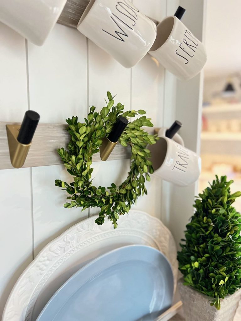 finished boxwood wreath hanging on a peg on a mug rack