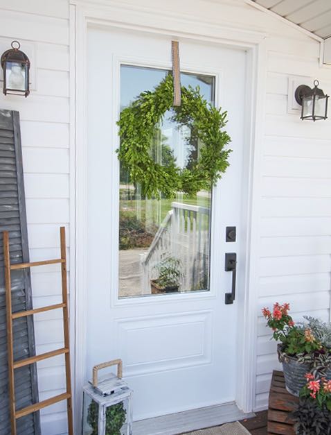 Exterior door on a side porch with a plain boxwood wreath hanging on it