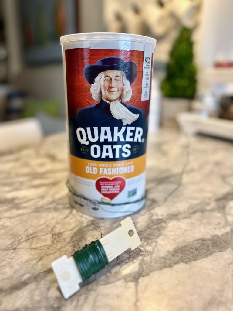 An oatmeal container and a paddle of florist wire are on a kitchen counter