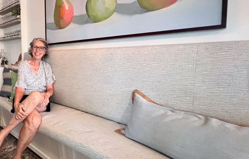 Smiling woman is sitting on the finished banquette cushion and leaning against the backrest