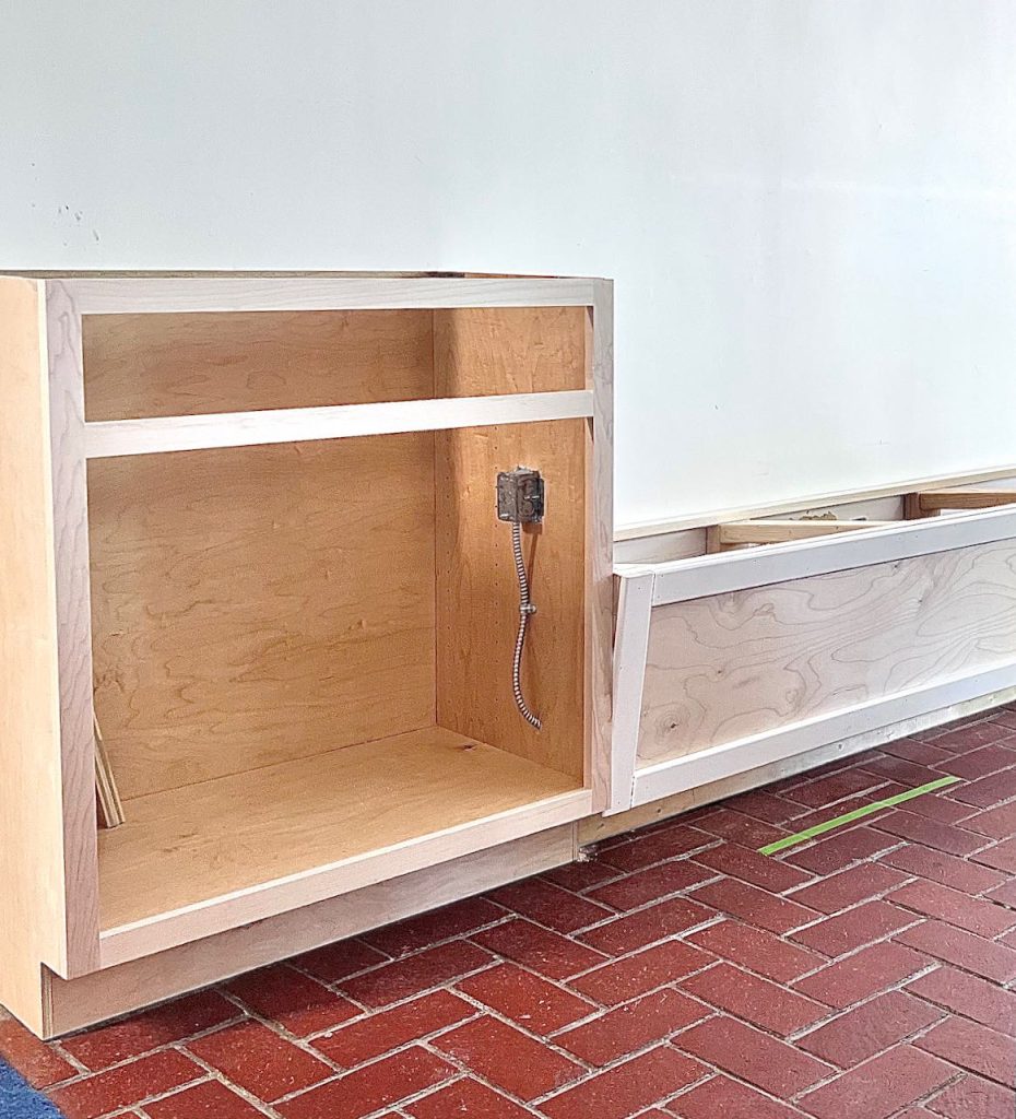 Cabinet box is installed on brick floor next to banquette box frame