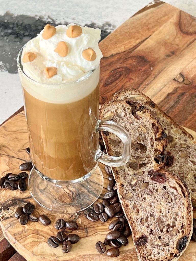 butterscotch latte and rustic bread are on a wood serving board