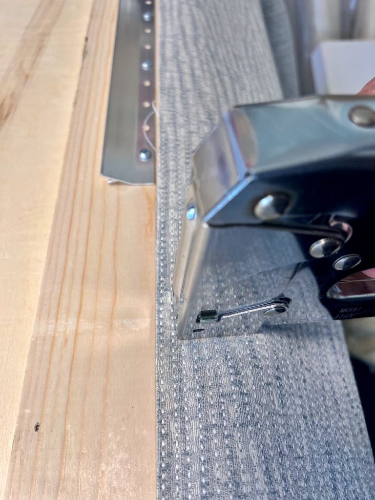 Closeup of stapler firing a staple through the fabric into the wood