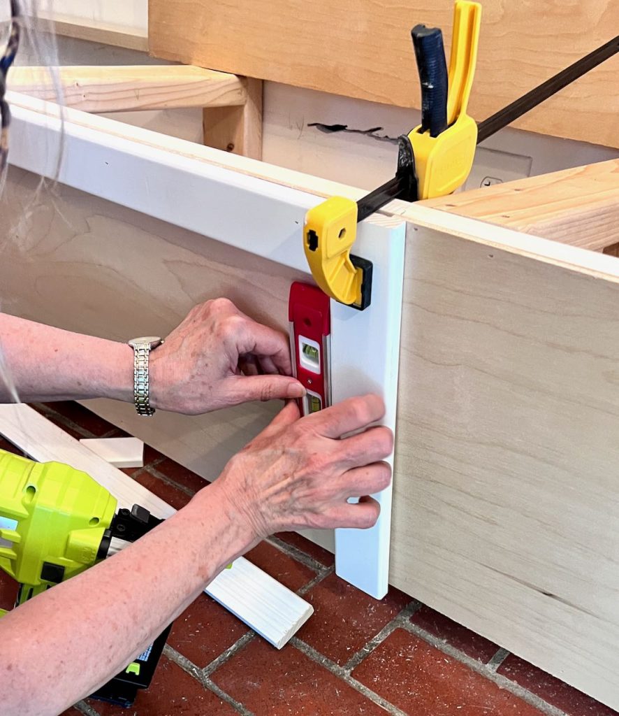 woman holding trim in place to add to the banquette seat