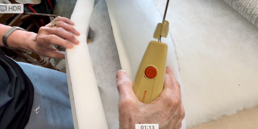 closeup of woman's hand showing the freshly cut foam with the electric knife in the other hand