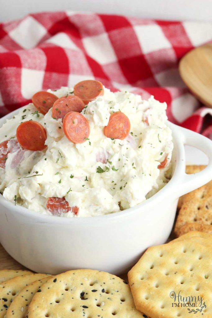 cold pizza dip in a bowl with a check napkin behind it