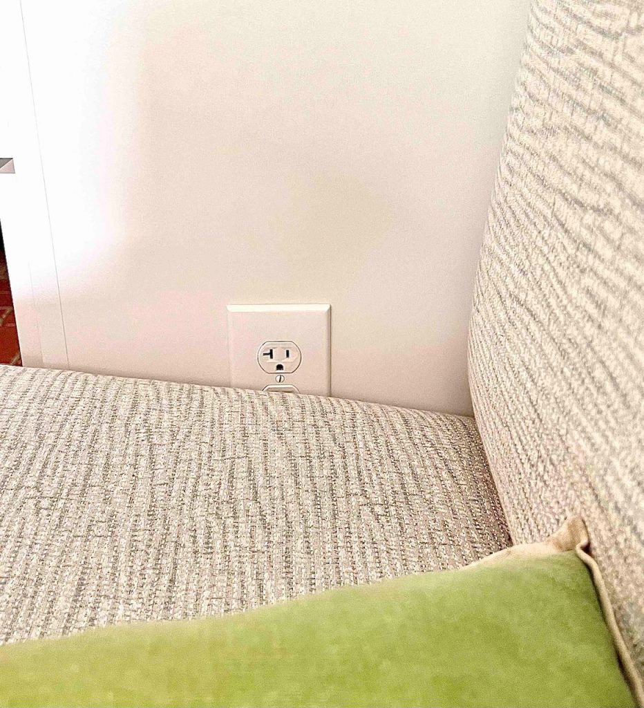 closeup of an outlet set into the side of the cabinet peeking out from the banquette cushion