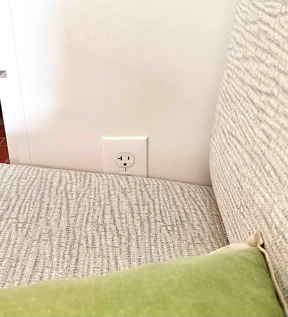 closeup of a power outlet on the side of the dry bar cabinet partially hidden by the banquette seat cushion