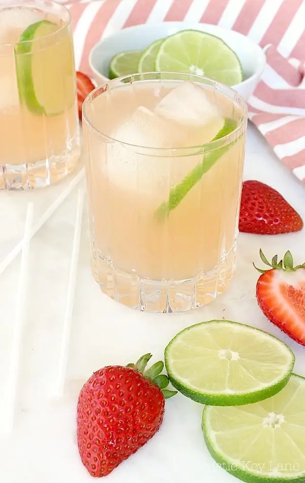 closeup of a glass beside a pitcher of strawberry lemonade margaritas