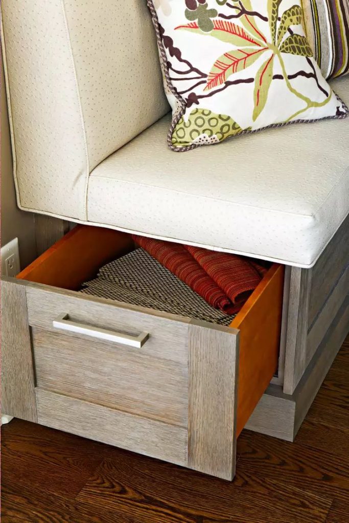 Closeup of a drawer filled with napkins and placemats opening out of the end of a built-in banquette