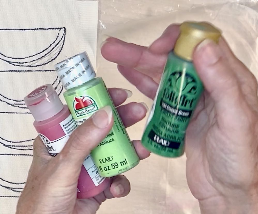 three bottles of craft paint in a woman's hands