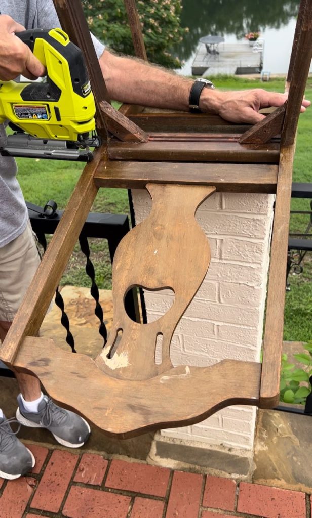 Man using a jigsaw to cut the back off a vintage dining chair