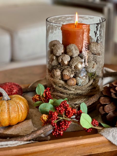 closeup of Candle hurricane surrounded with Fall berries and pumpkins