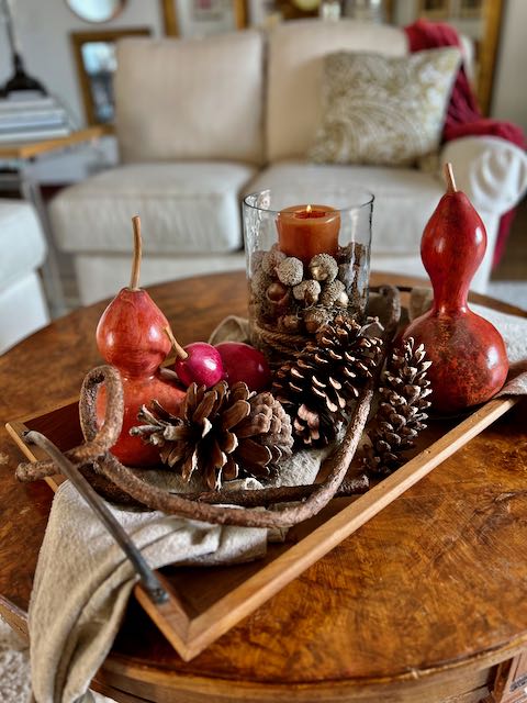 3 dyed gourds with large pinecones accent a pillar candle in hurricane with acorns