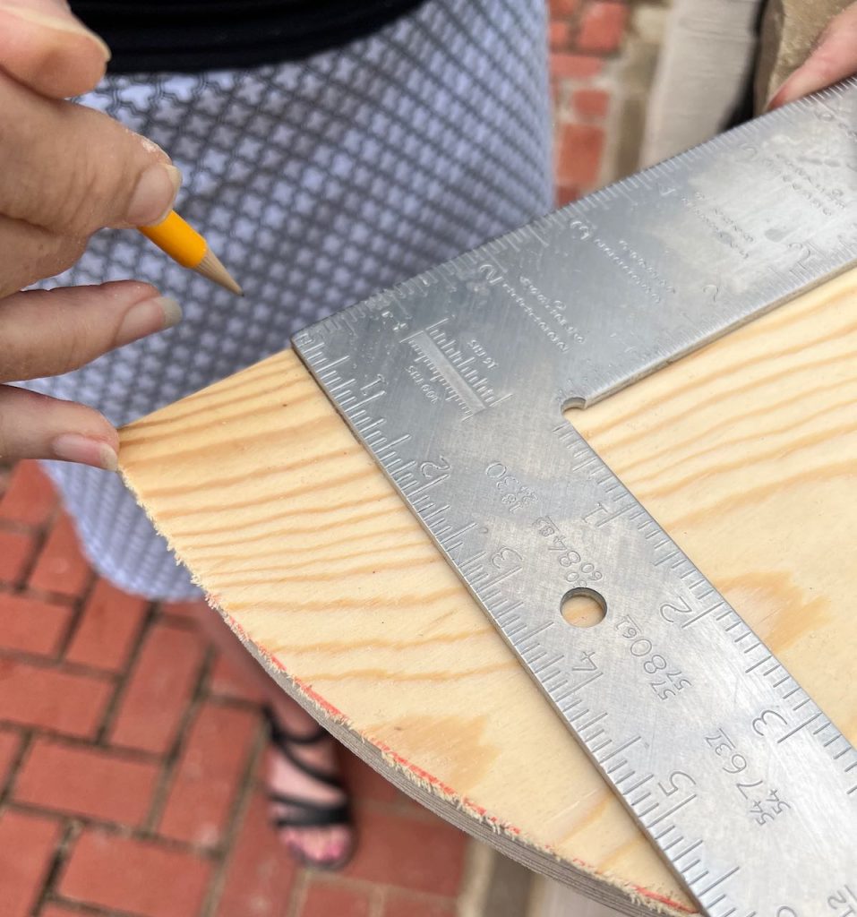 closeup of woman using a carpenter's square to mark cut lines for the notches