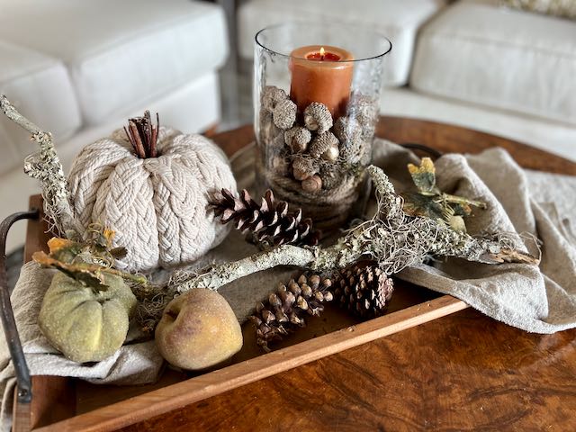 Neutral Fall Arrangement on a tray with a candle hurricane, acorns, pumpkins, pinecones and branch