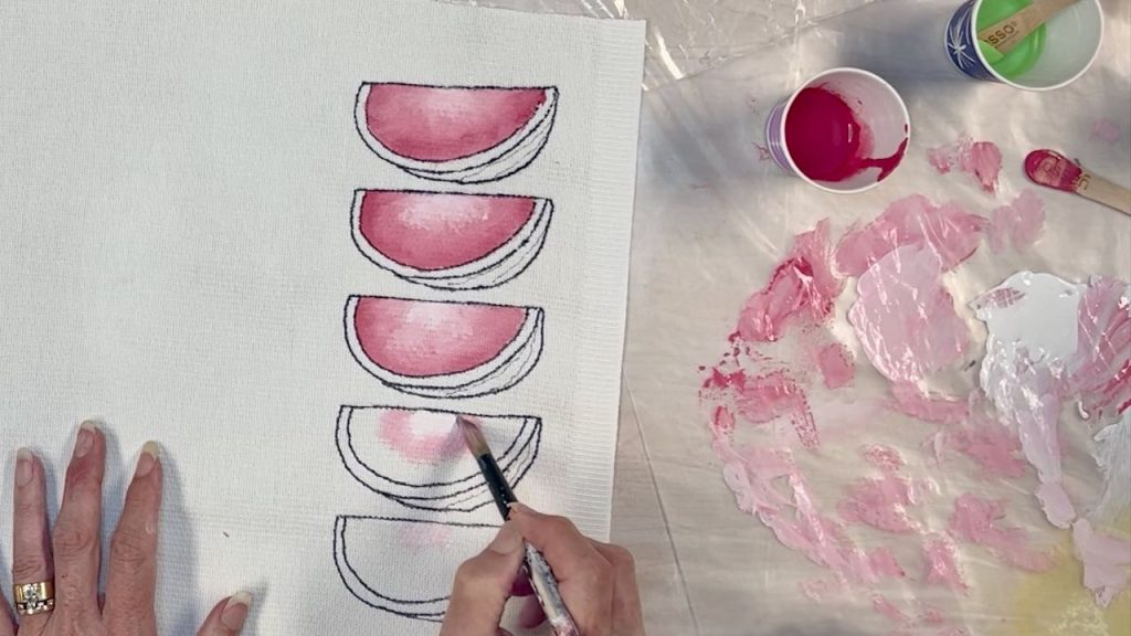 woman holding a paint brush and painting the meat of the watermelon