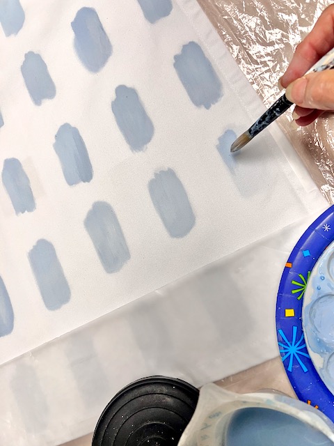 woman's fingertips holding a paintbrush and painting the last brushstroke in a row