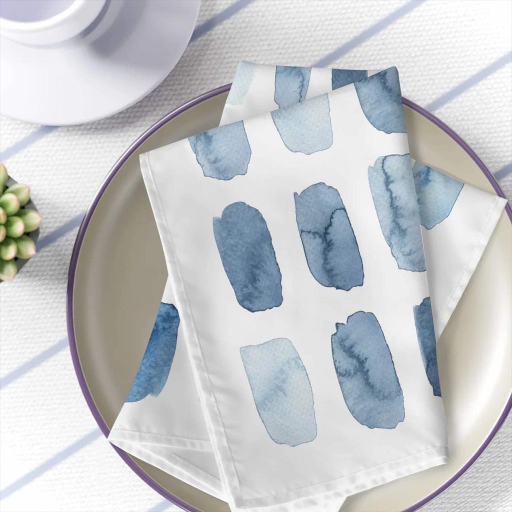 white napkins with watercolor blotches is folded on a stoneware plate