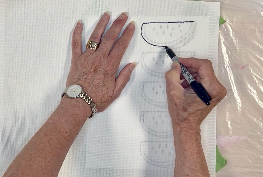 woman's hands holding a marker and tracing the design onto fabric