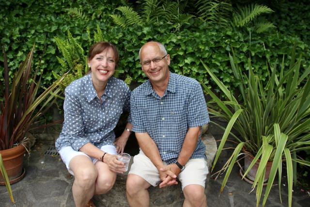 a man and woman in coordinating outfits sitting on a garden wall