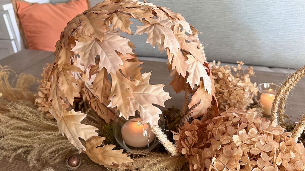 closeup of large leaves and rope globe with a candle inside surrounded by dried hydrangea