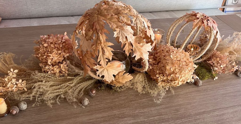 Full centerpiece of dried grasses, hydrangeas and acorns with two leaf and rope globes