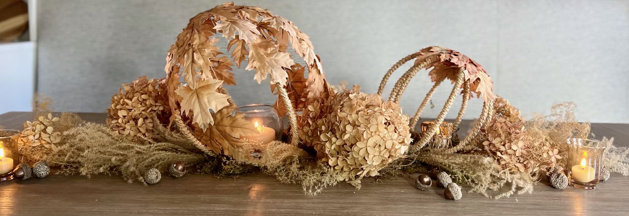 wide and tight image of the full centerpiece of dried grasses, hydrangeas and acorns with two leaf and rope globes