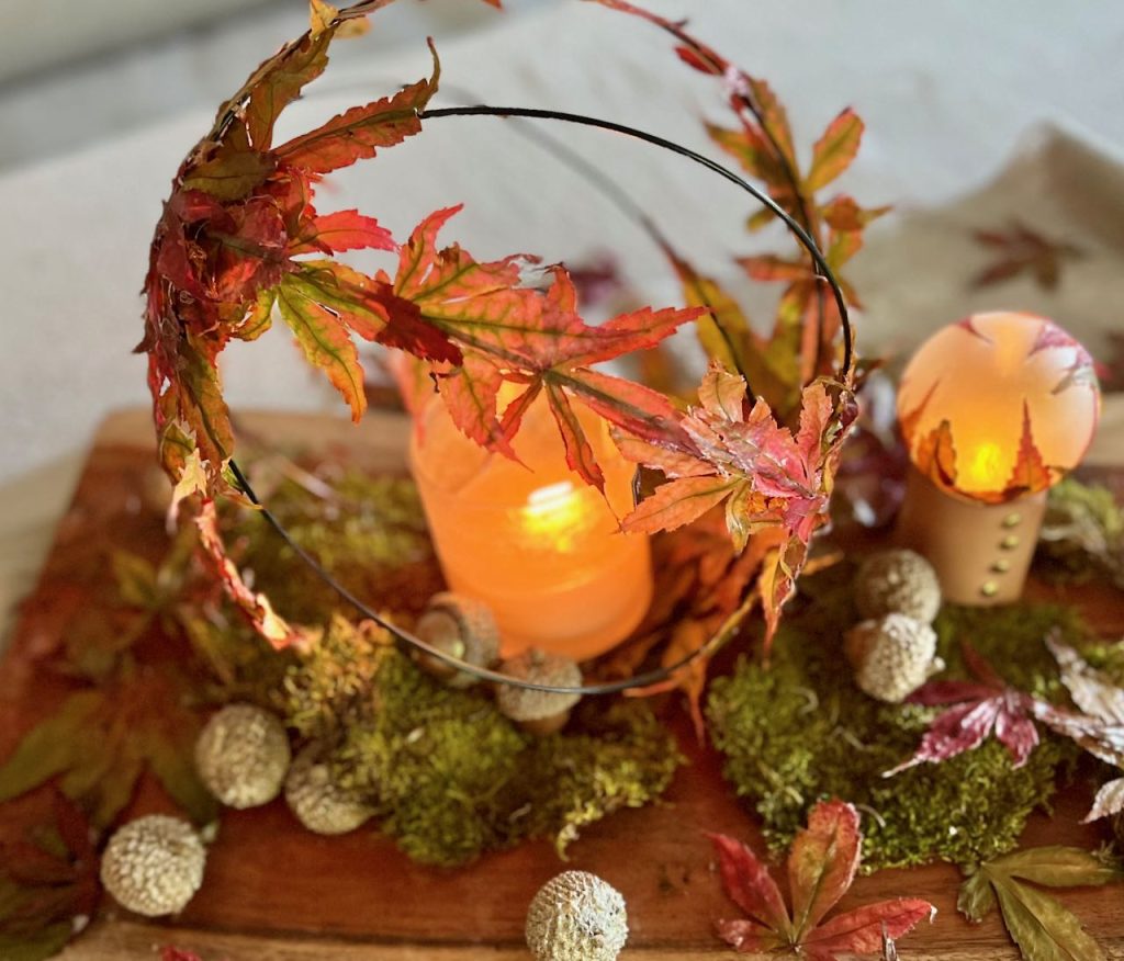 a candle is glowing inside a garden globe that's covered with preserved Fall leaves