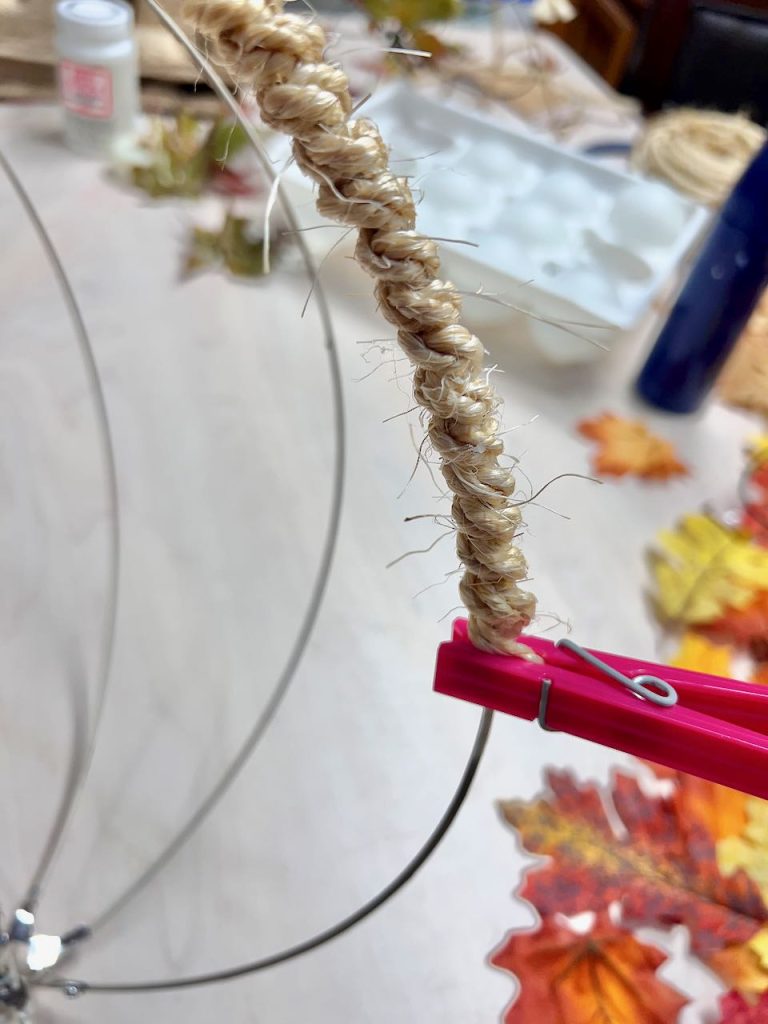 closeup of a clothhespin holding the end of the rope glued onto the wire frame