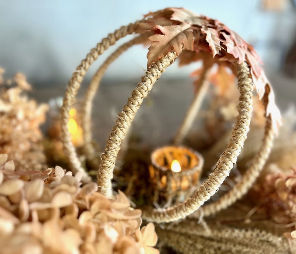 close up of a candle in a rope cup inside the small rope and leaf globe