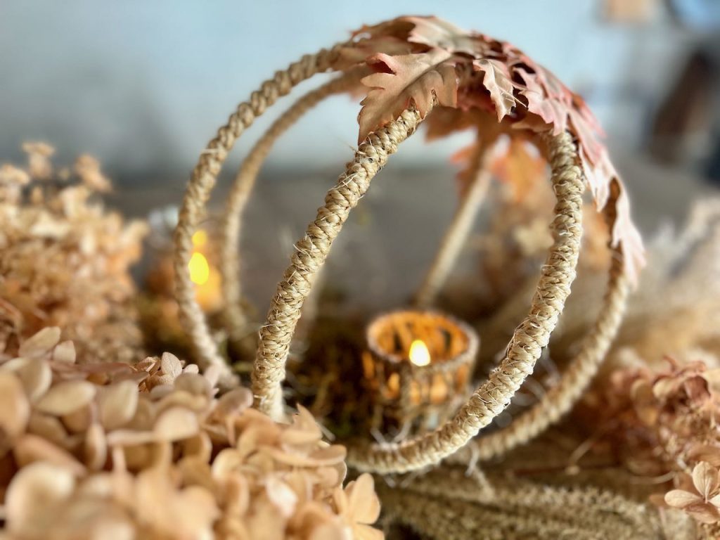 close up of a candle in a rope cup inside the small rope and leaf globe