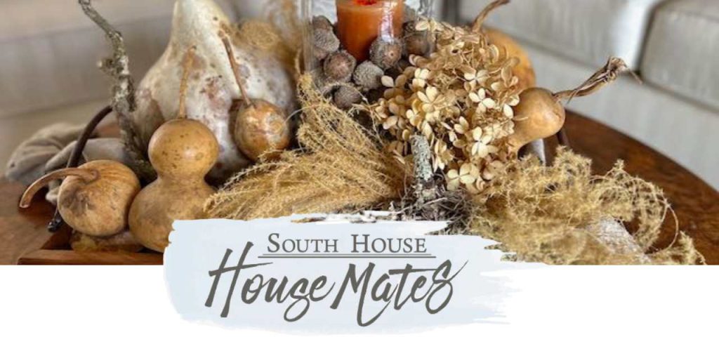 Fall Foraged arrangement on a round wood coffee table above the logo for South House "House Mates"
