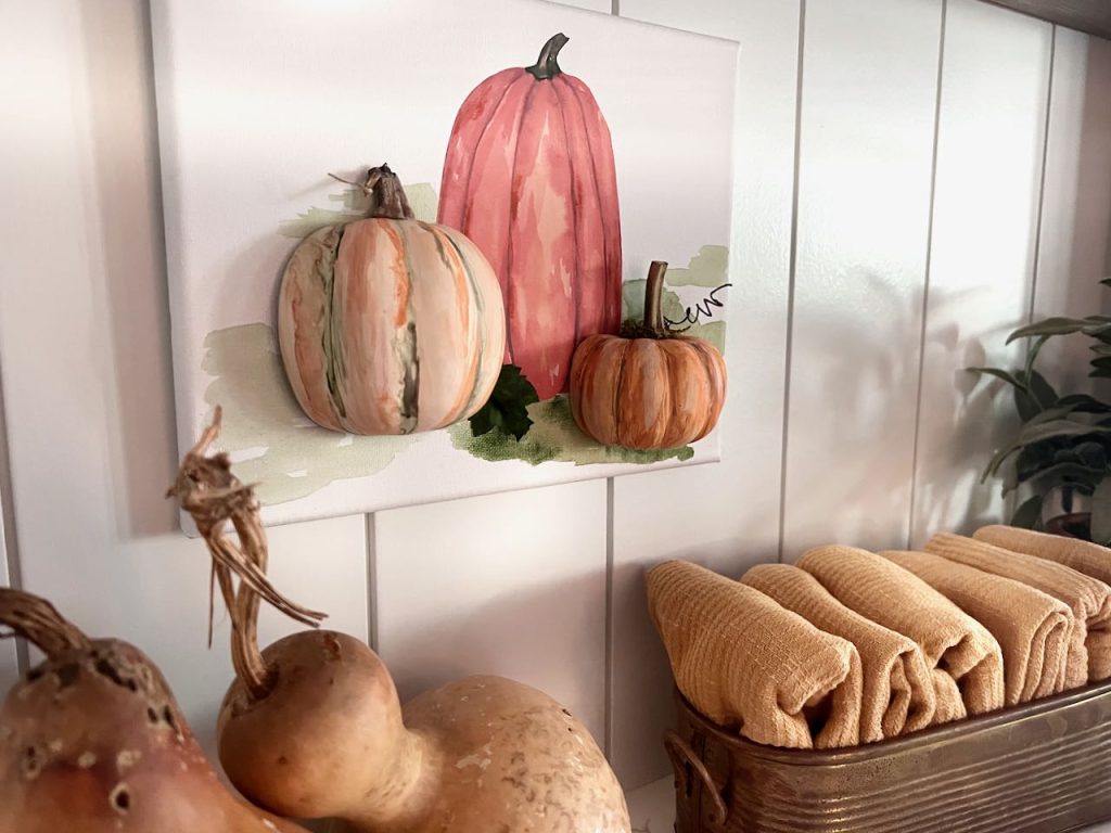 closeup of 3D pumpkins on a stretched canvas hanging as wall art above some gourds