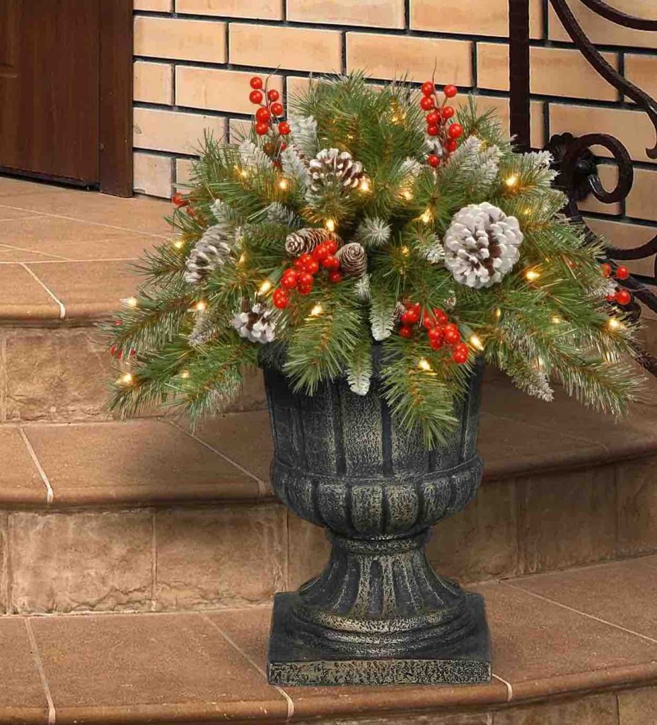 outdoor pot shown filled with lighted Christmas greenery