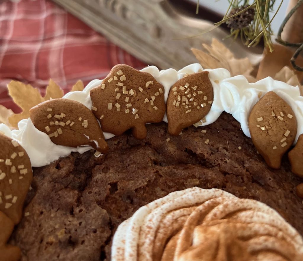 closeup of details of little gingerbread leaves with gold sparkles resting on the whipped cream edging
