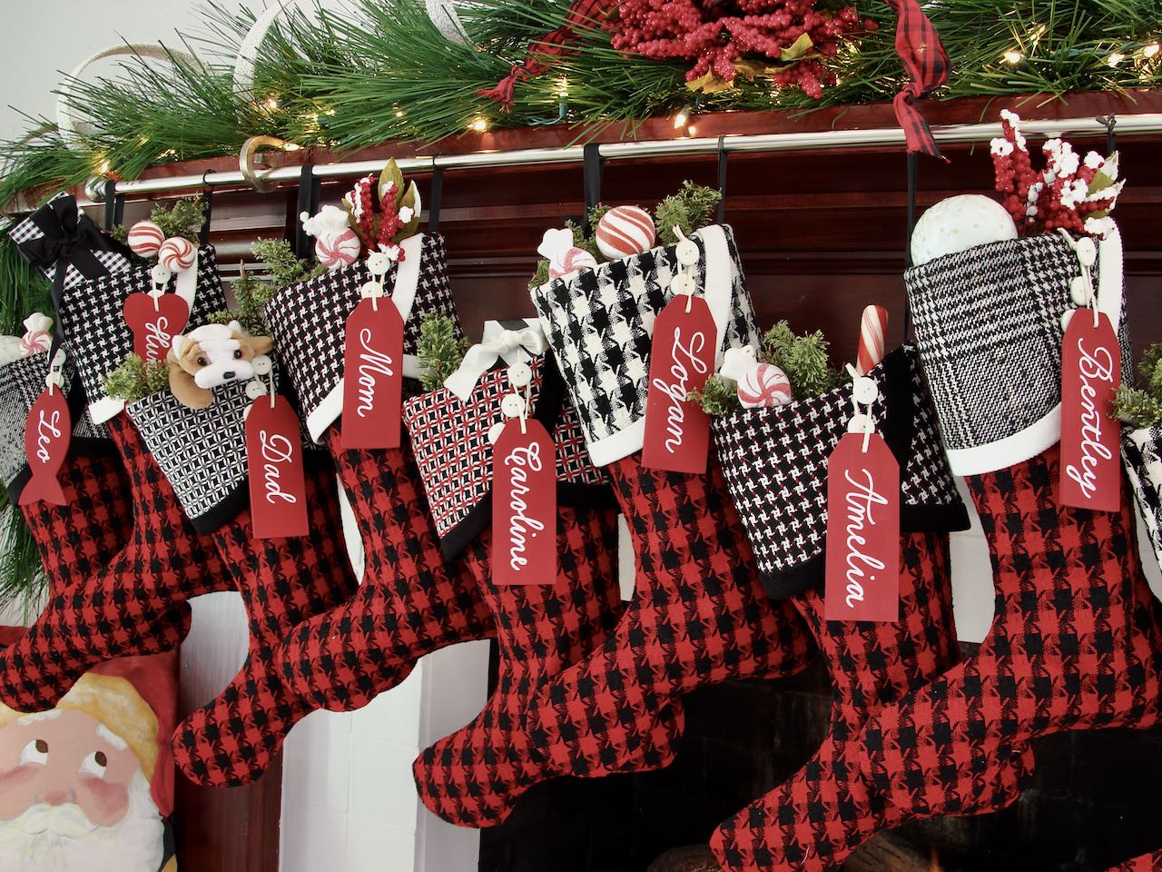 8 coordinating yet unique Christmas stockings are hanging from a mantel. Large wood name tags hang from the top of three buttons on each cuff