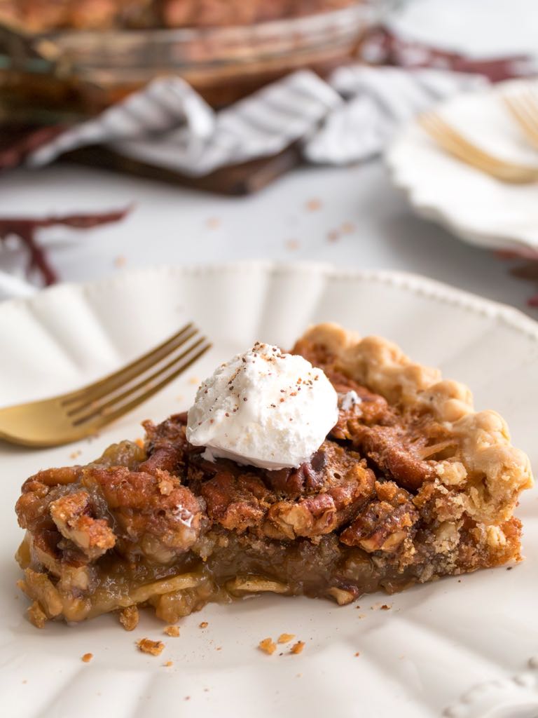 slice of pecan pie with a dollop of whipped cream on a plate