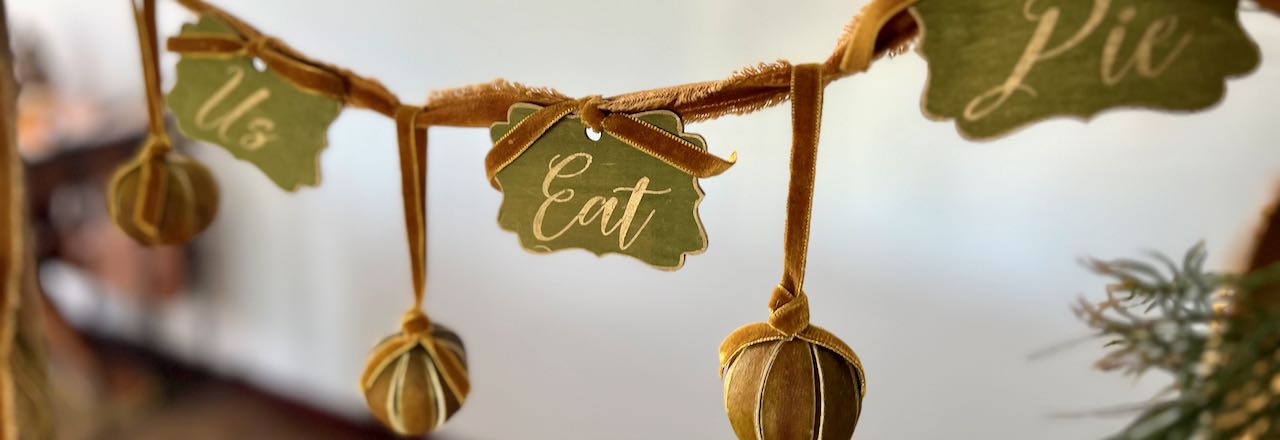 wide closeup of signs and dried limes hanging from a "Let Us Eat Pie" garland