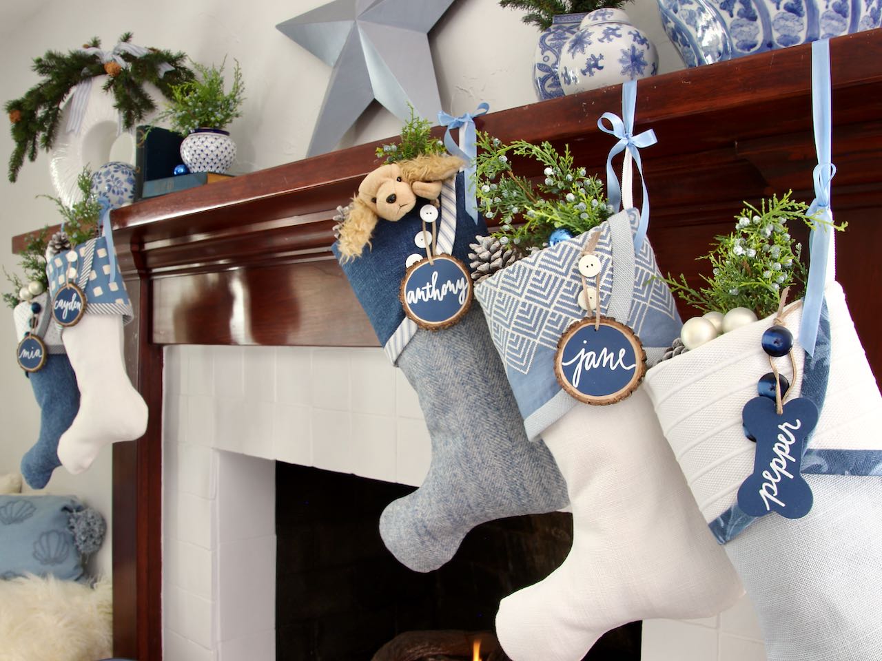 5 coordinating yet unique Christmas stockings are hanging from a mantel fflanking a fire. Tree slice name tags hang from the top of three buttons on each cuff