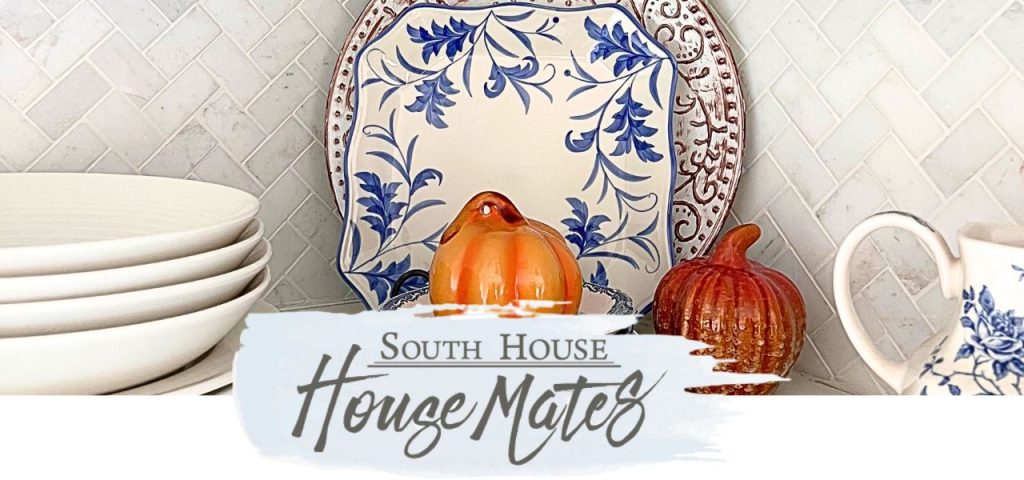 ceramic pumpkin on a pile of small mismatched plates in front of a share plate and a round plate standing in the corner of open shelves