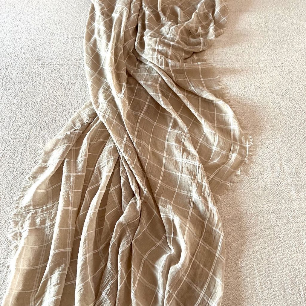 closeup of tablecloth with a thin plaid shawl twisting and turning down the center of the table